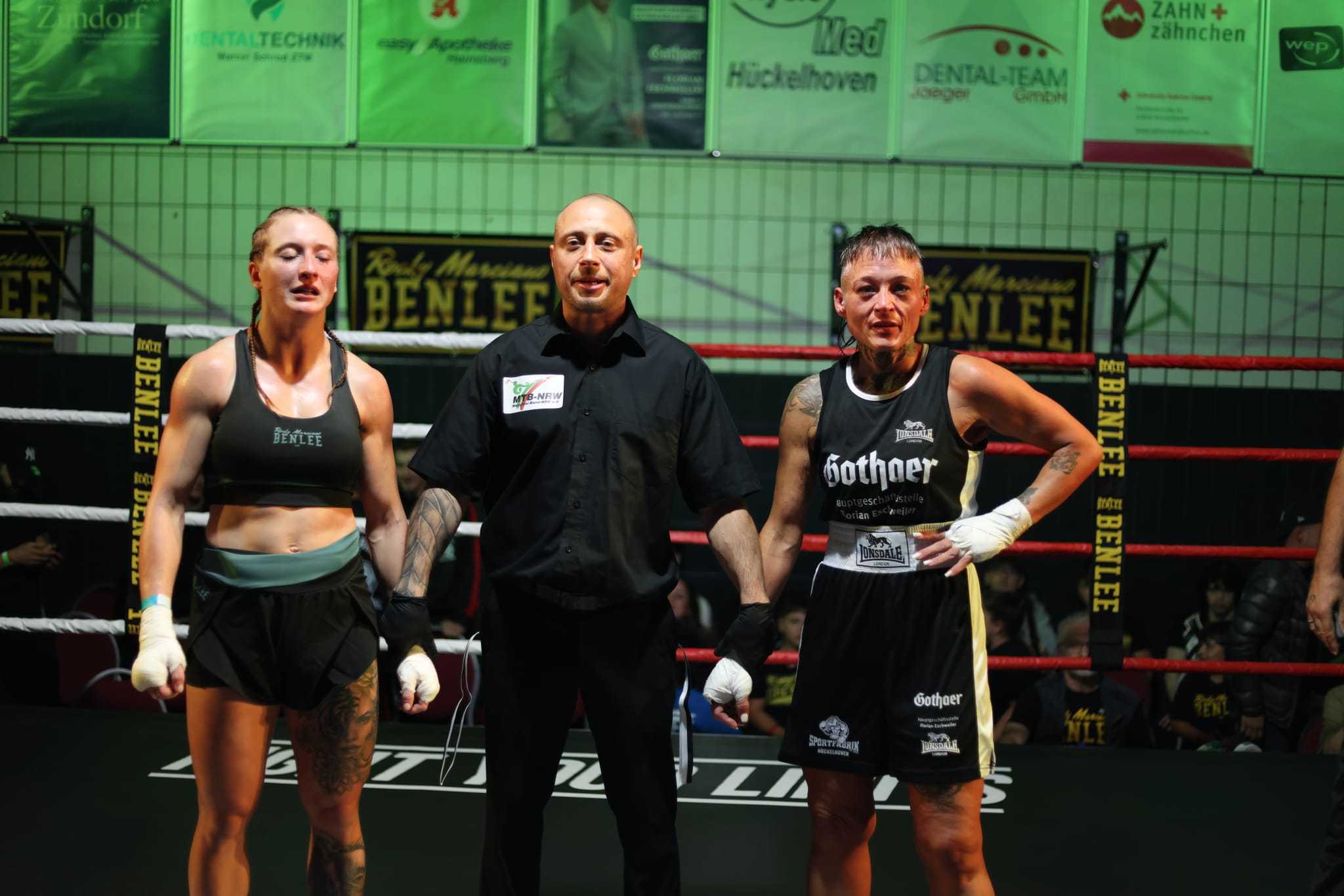 Sue Winkens und Martyna Zebyk nach ihrem Kampf bei der NeverGiveUp Fightnight 2026 in Hückelhoven mit dem Ringrichter im Boxring